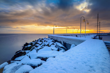 Early morning at frozen and snow covered pier at beach in Sopot. Winter landscape. Poland.