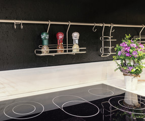 Stylish kitchen in the style of high-tech. Kitchen apron of painted wood and ceramics, metal railing and a modern electric ceramic hob built into the marble tabletop