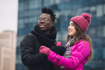 Two multiracial students friends together in winter city looking on side