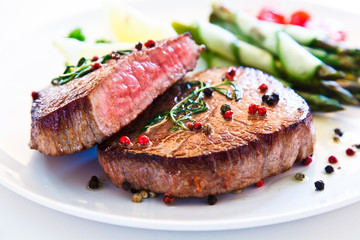 Grilled beefsteak with asparagus on white background 