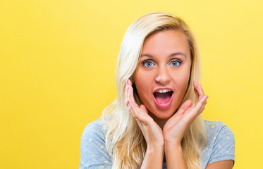 Surprised and excited young woman posing on a solid background