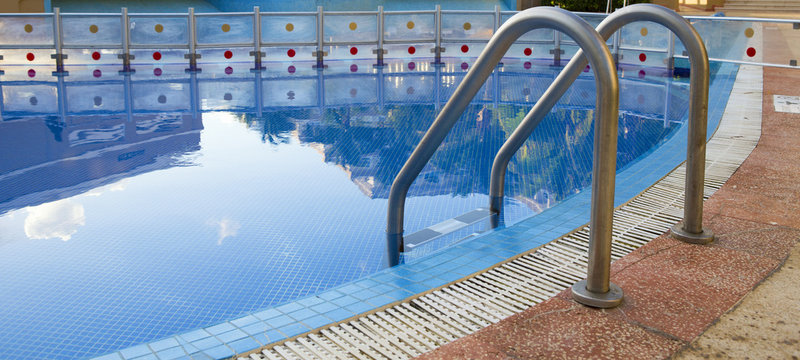 Pool water reflections. Ladder on the edge. Image suitable for banners and cover photo use.