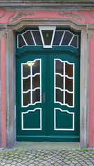 Dark green wooden door with white-framed window panes