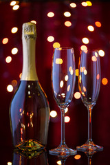 Bottle of champagne and two empty glasses in New Year's bokeh