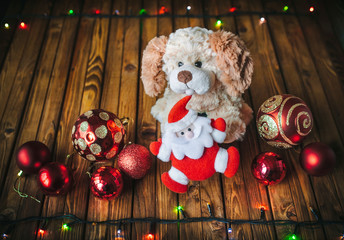Dog, Santa Claus, red Christmas balls, garland on a wooden background.