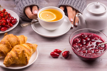 girl's hands in a warm sweater and a cup of tea with jam and croissant - Winter Breakfast