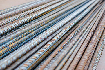 A number of steel rods or deformed rebars used in reinforced concrete with some corrosion. Diagonal pattern