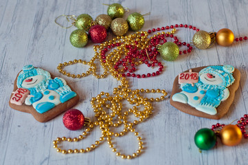 Holiday Christmas gingerbead in shape of snowman laying near colorful decorations on light wooden background