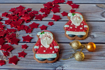 Christmas gingerbread. Two Santa figures laying near decorations, stars, balls on wooden background