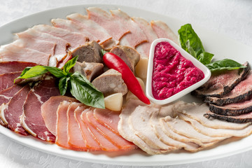 Assortment of cold meats plate on a white background, restaurant served top flat view, overhead.