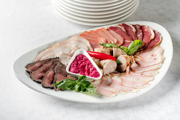 Assortment of cold meats plate on a white background, restaurant served top view, overhead.