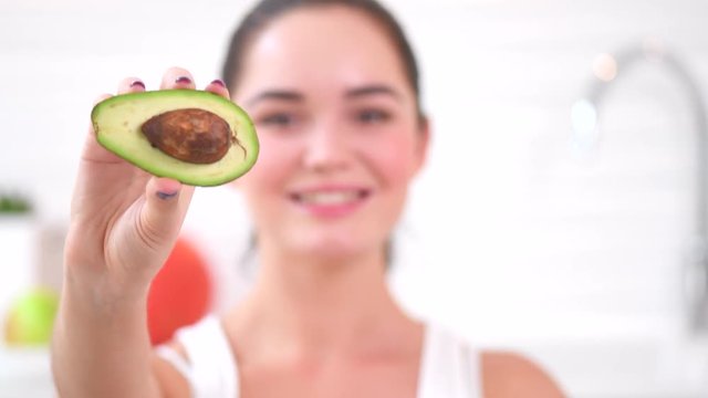 Beauty young joyful woman holding fresh avocado. Healthy eating concept. 4K UHD video footage. Ultra high definition 3840X2160