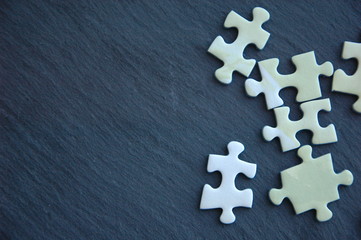 Obraz premium A lot of white and gray puzzles on a black background.