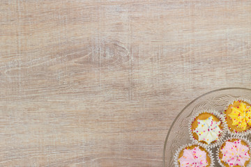 Colorful cupcakes on a wooden table background.