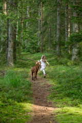 Flicka och hund springer på en stig i skogen