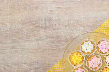 Colorful cupcakes on a wooden table background.