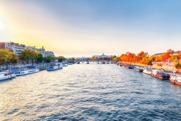 Obraz premium Paris, France. View on the city over Seine river. Autumn sunset scenery. Exhibition hall in Grand Palace (Palais) in background and yellow fall trees on river banks.
