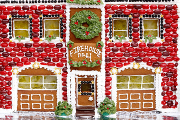 Homemade Christmas holiday firehouse ginger bread house with white frosting and green and white jelly bean candies decorating facade