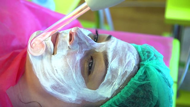 A young girl at a reception with a cosmetologist. Face cleaning. Darsonvalization.
