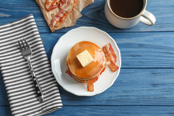 Plate with tasty pancakes and bacon on table