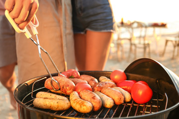 Man cooking sausages and vegetables on barbecue grill, outdoors