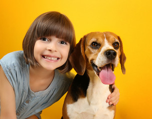 Cute girl with dog on color background