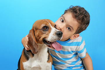 Cute boy with dog on color background