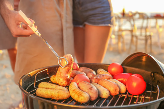 Man cooking sausages and vegetables on barbecue grill, outdoors