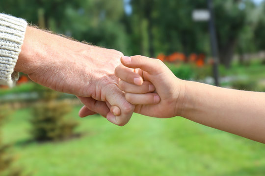 Senior man and his grandchild making pinky promise on blurred background
