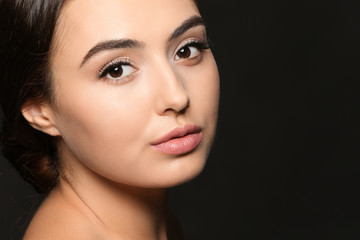 Fototapeta premium Beautiful young woman with eyelash extensions on dark background