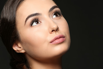 Fototapeta premium Beautiful young woman with eyelash extensions on dark background