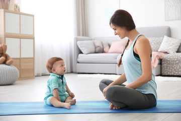 Fototapeta na wymiar Young mother doing yoga with baby at home