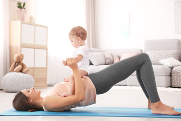 Young mother doing yoga with baby at home