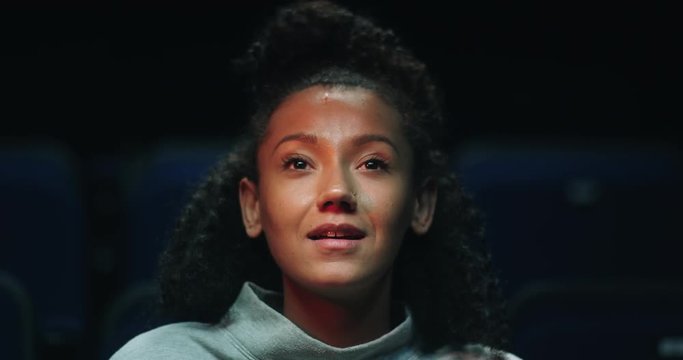 Close up of a beautiful, smiling young woman enjoying a movie at the cinema.
