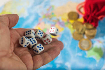 Male hand throwing dice on the table with a world map and money. The concept of ownership of the...