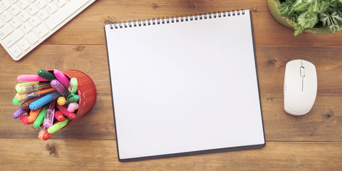 Blank notebook paper, keyboard, mouse and pens on wood table background, banner, with copy space for text business and technology background, top view, flat lay
