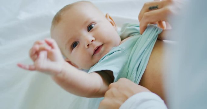 Mother dressing adorable young baby