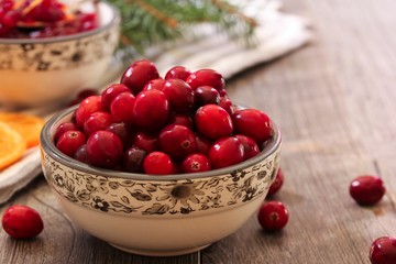 Fresh Cranberries in a bowl on wooden background, selective focus