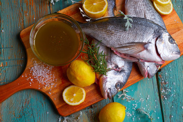 Sea bream with lemon rosemary and marinade on blue wood background
