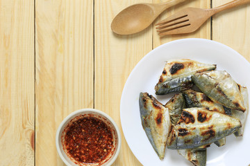 grilled fish of thai foods in white dish on wooden floor.