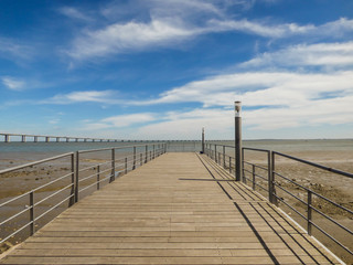 Fototapeta premium Fishing rods at a pier by the Tagus river at Parque das Nacoes - Vasco da Gama bridge in the background (Lisbon, Portugal)
