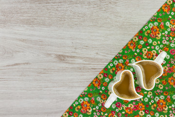 Cappuccino on pattern flower cloth napkin on empty wooden background. Top view with space for your text.
