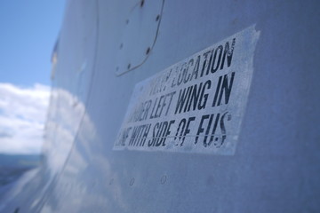 a close-up on a faded, worn sign on the side of an old airplane