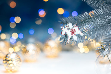 Fototapeta na wymiar christmas tree decorations on silver branch against blurred background with holiday lights