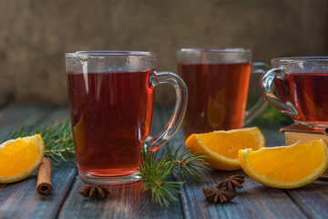 Tea in a glass mug, cinnamon stick, orange and fir branch.