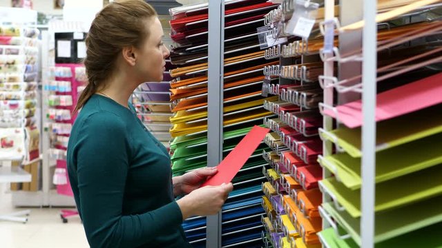 Beautiful woman buying  colored paper in supermarket.