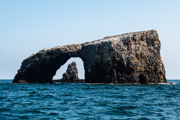Arch Rock natural bridge with a volcanic rock formation in the background at East Anacapa Island in...