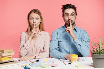 Portrait of female and male office workers or students show silence sign ask to be quiet as there...