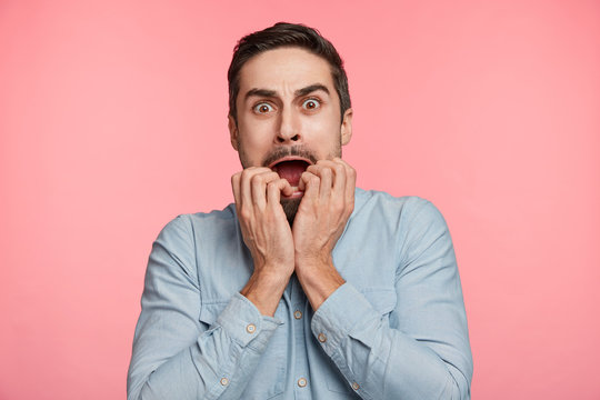 Portrait of anxious scared bearded male looks nervously at camera, worries about girlfriend`s health, who is in difficult situation after car accident. Panic young man recieves shocking news