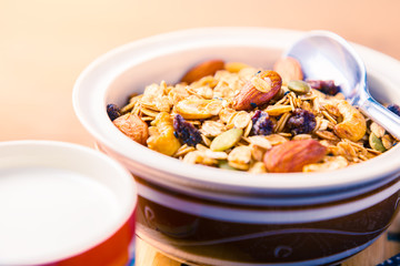 closed up of multi-grain cereal with dried fruits and nuts in an asian style bowl with cup of milk